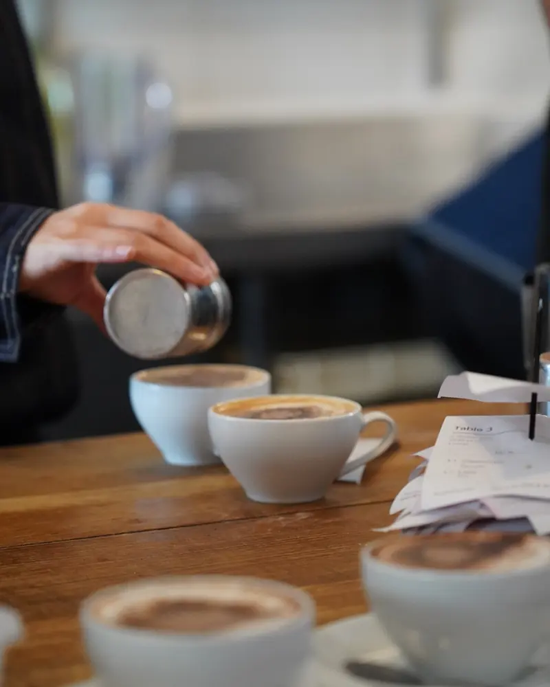 Chocolate dusted over cappuccinos on the bar